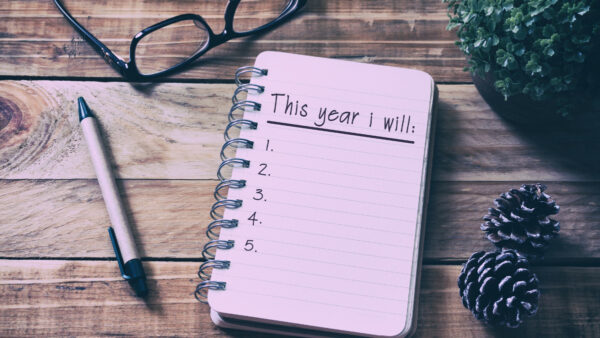 Notepad, pen, and glasses listing new year resolutions