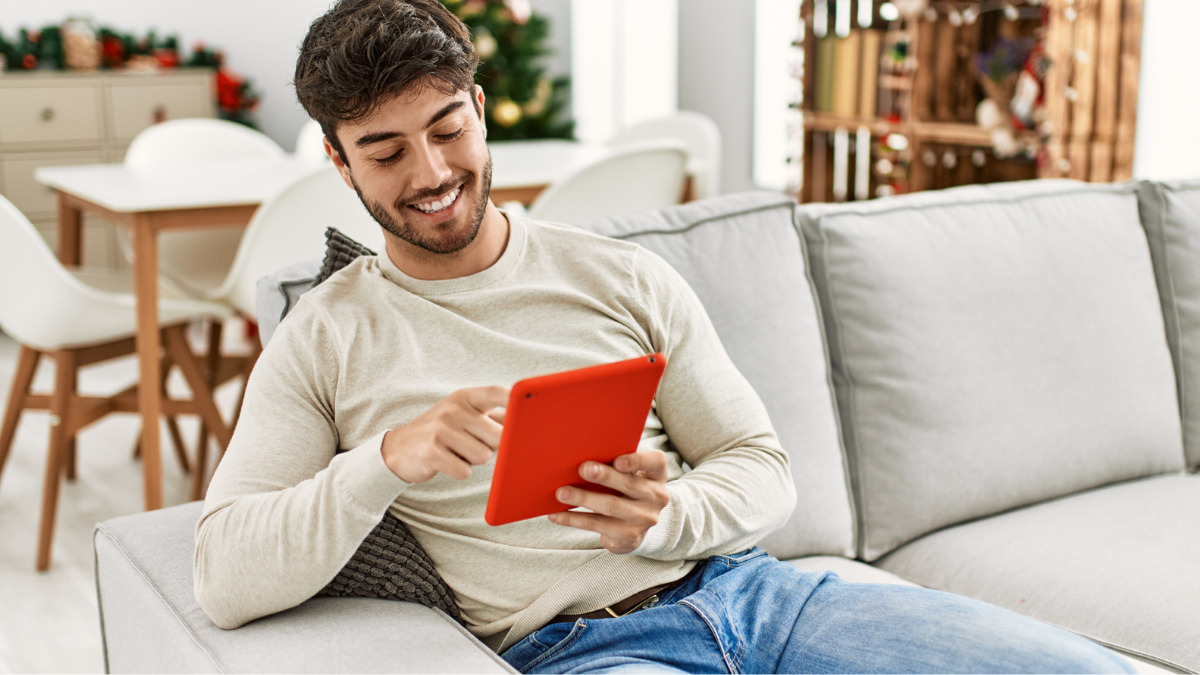 Man sits on sofa and looks at tablet