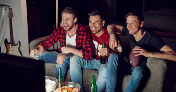 Three men sitting enjoying the Super Bowl wathcing TV